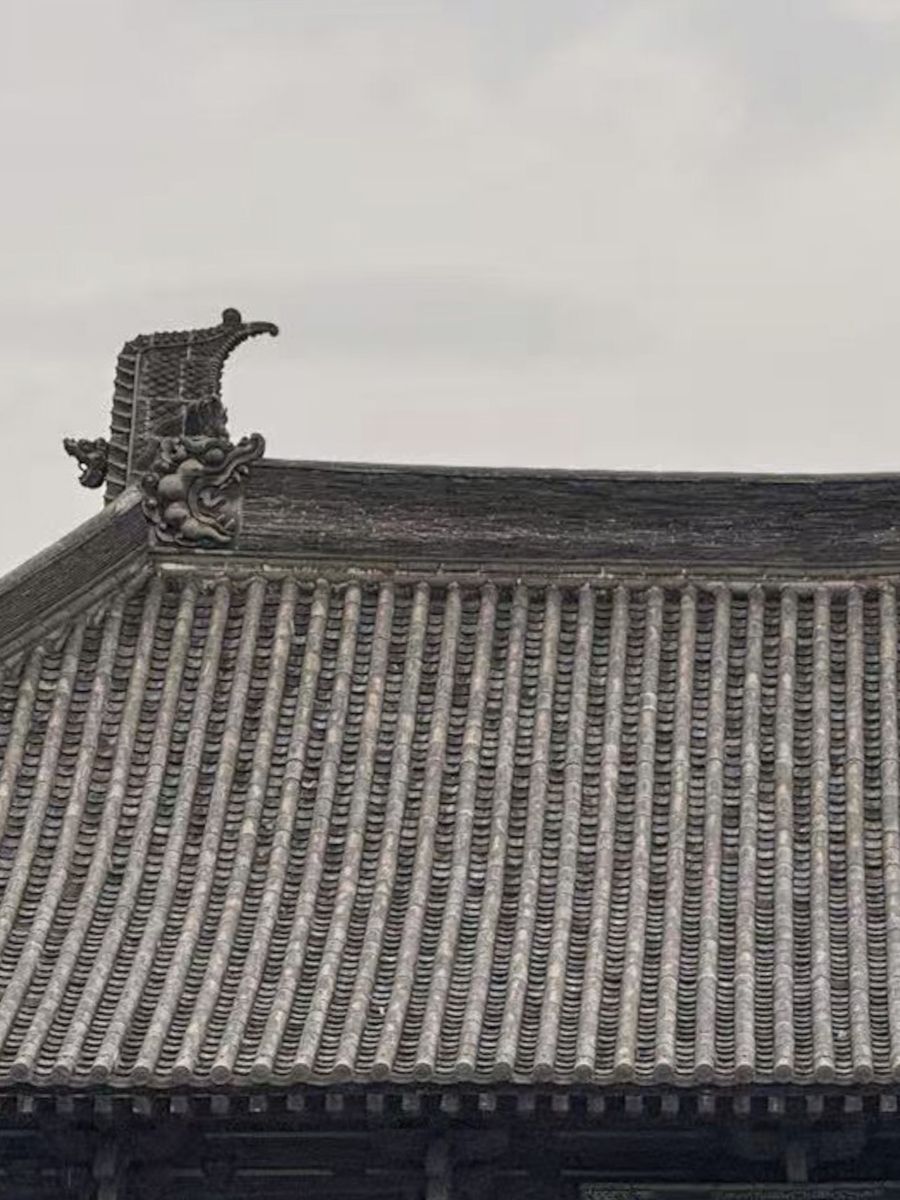 A grey tiled temple roof with a dragon ridge ornament