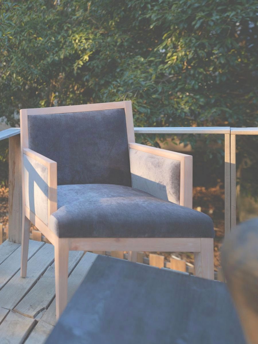 A grey-blue armchair on a timber deck